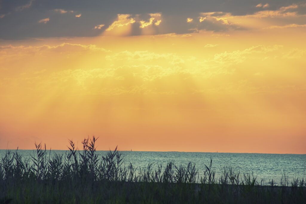 Peaceful sunlight shining down on the sea in the distance from the dunes of the beach