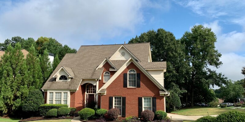 Family home in a neighborhood with green lawn, blue sky and clouds