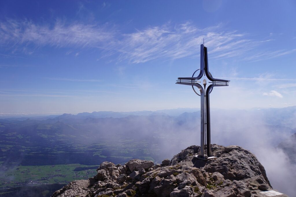 The cross of Jesus on a mountain top with blue sky and the presence of a cloud